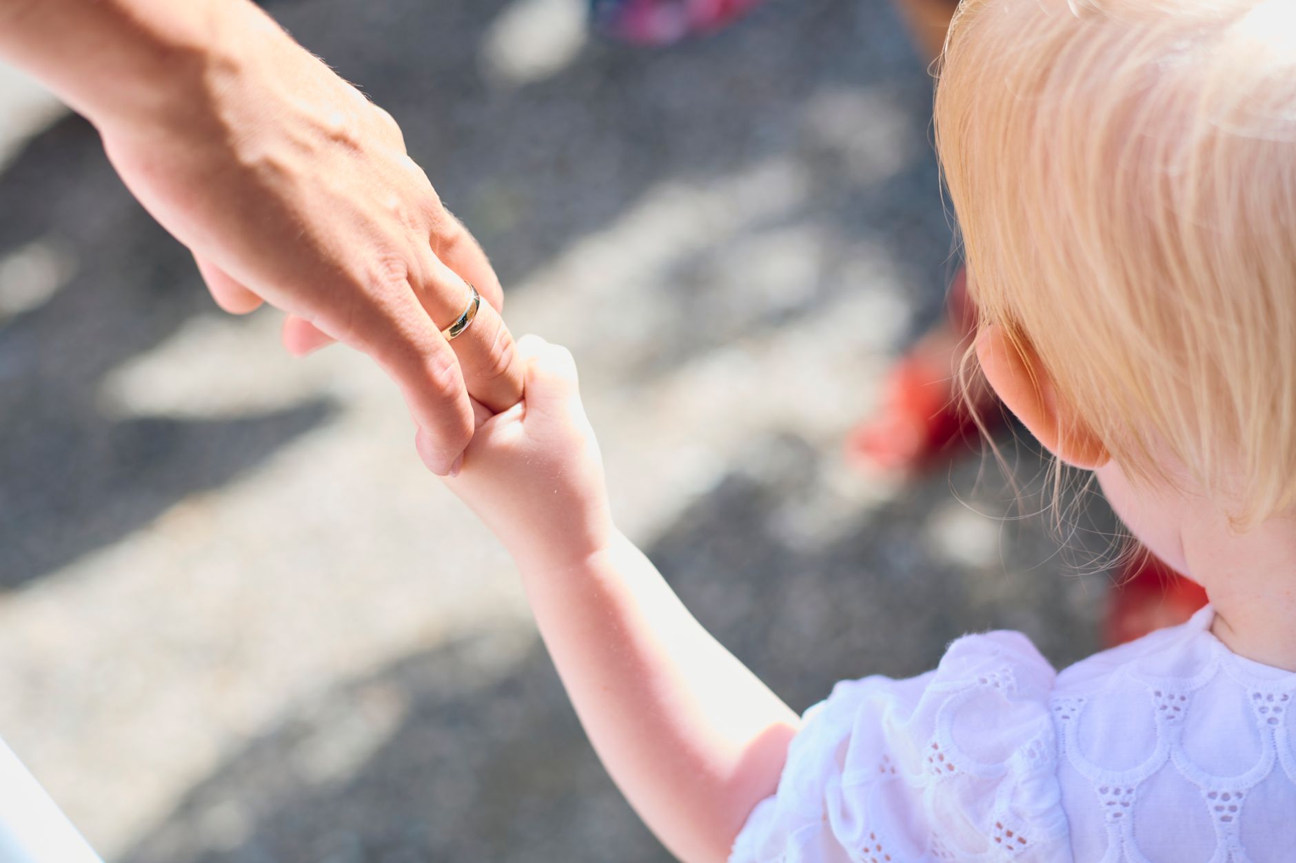 A child holding a parent's hand while walking outdoors