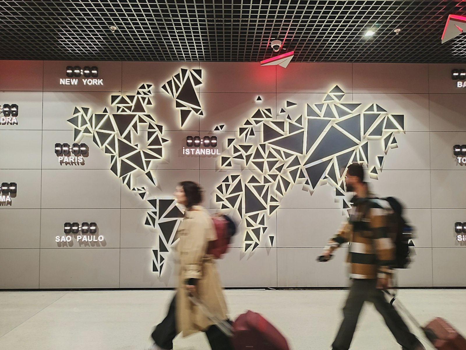 Two travellers with suitcases in front of a glowing world map