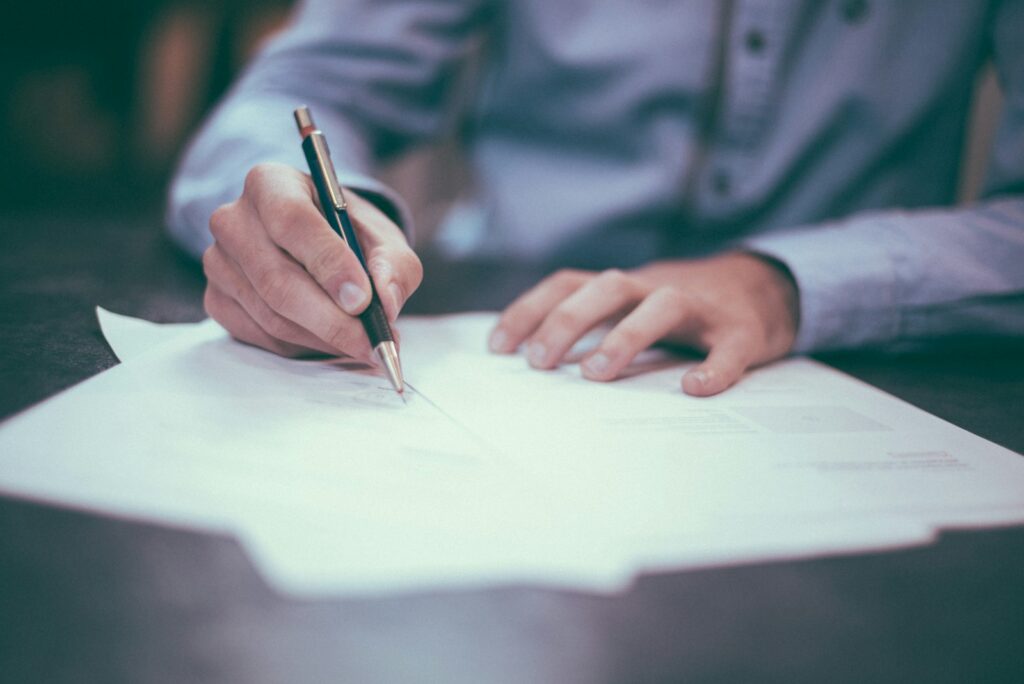 Рука подписывает документ "Sign here" – изменение имени или фамилии